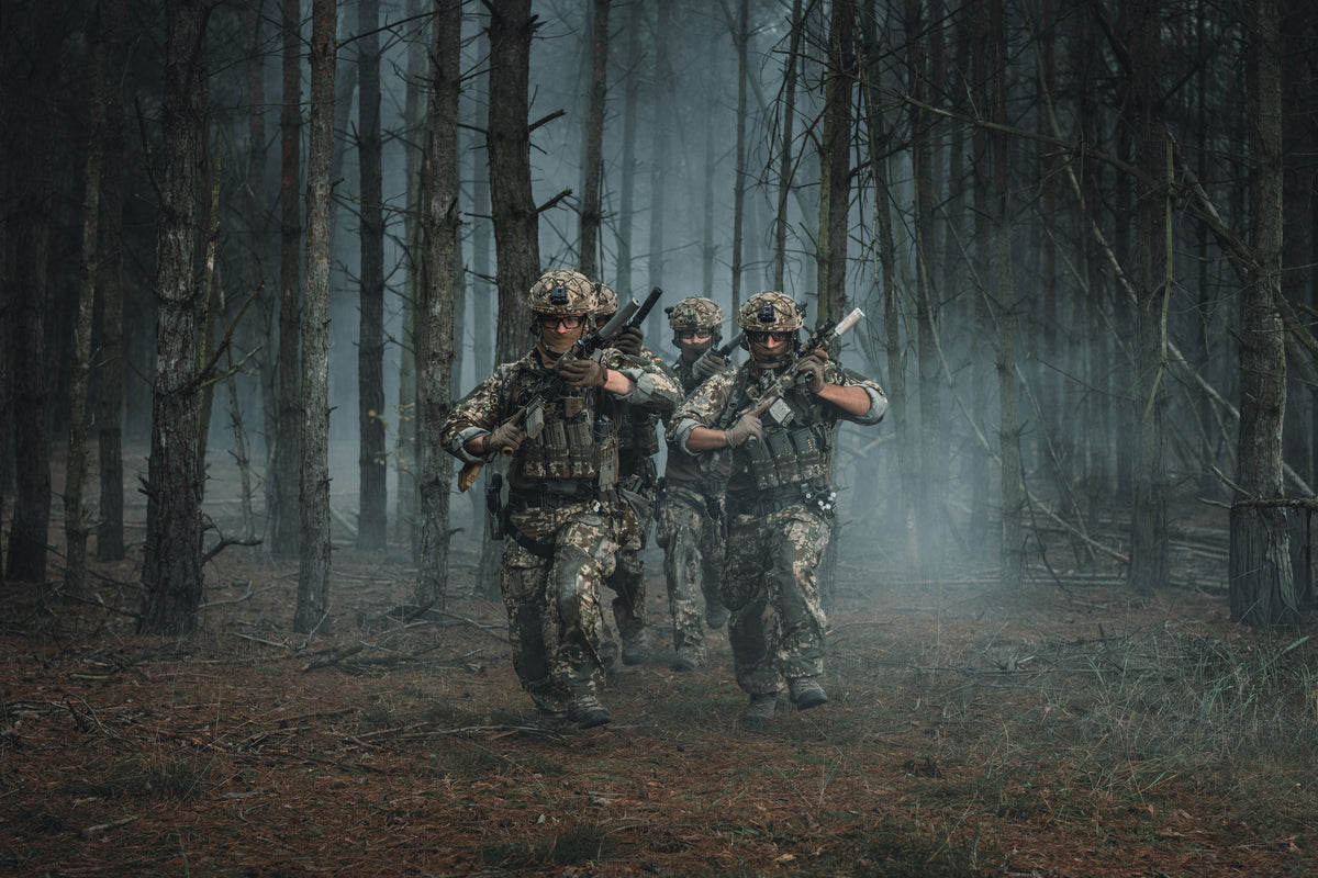 Bundeswehr soldiers in a training situation walking through a forest at night.