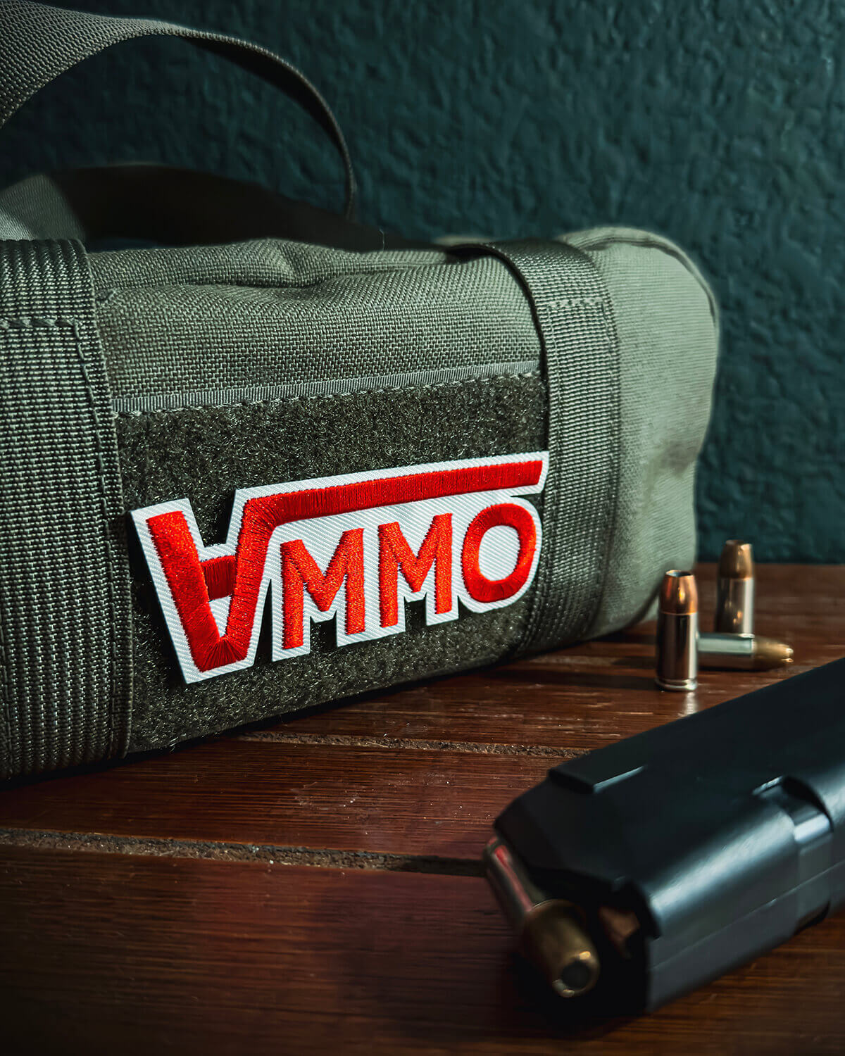 Green roll-up bag with 'AMMO' patch on a wooden surface with a magazine and bullets.