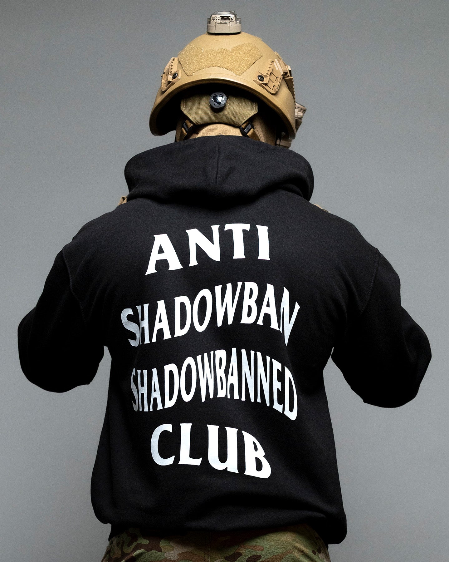 Person wearing a black hoodie with text on the back, standing against a gray background. #color_black