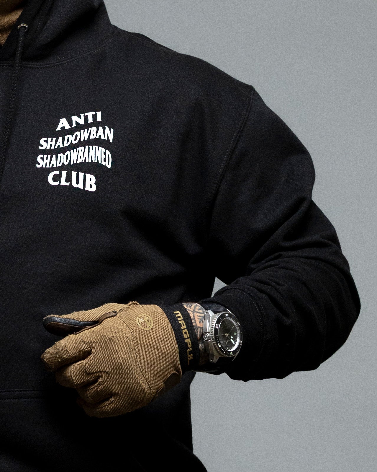 Black hoodie with text and brown gloves on a gray background. #color_black
