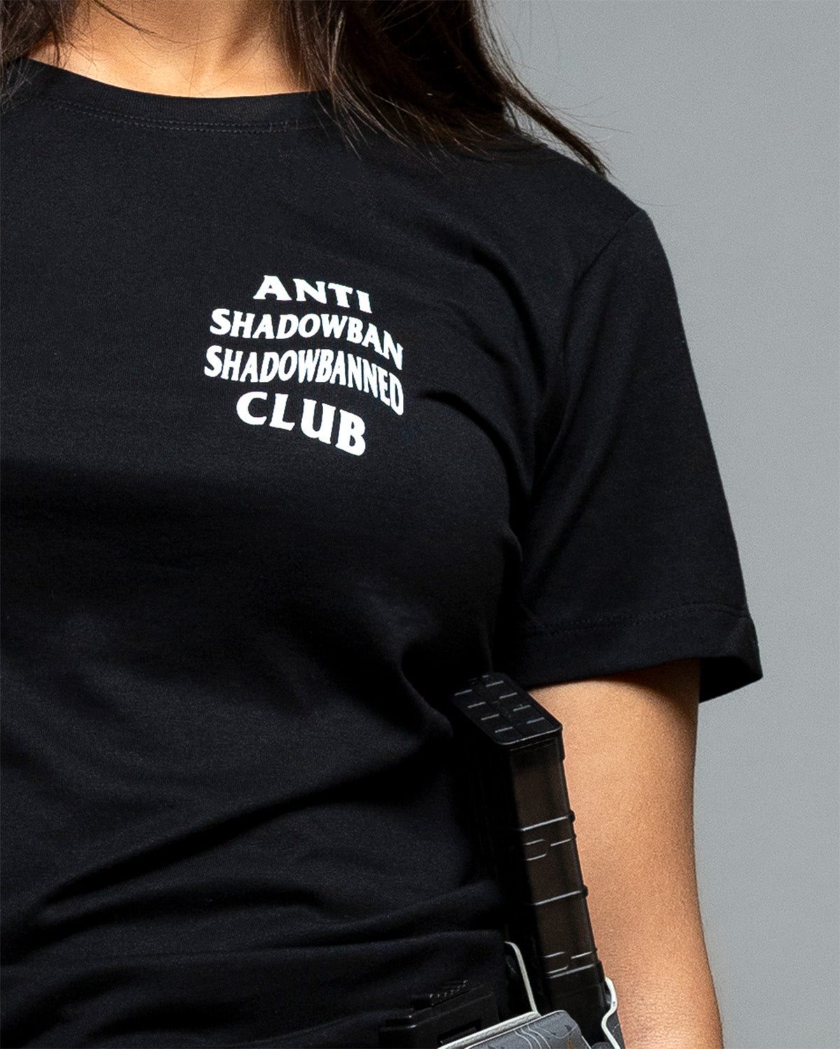 Person wearing a black t-shirt with white text on a gray background. #color_black