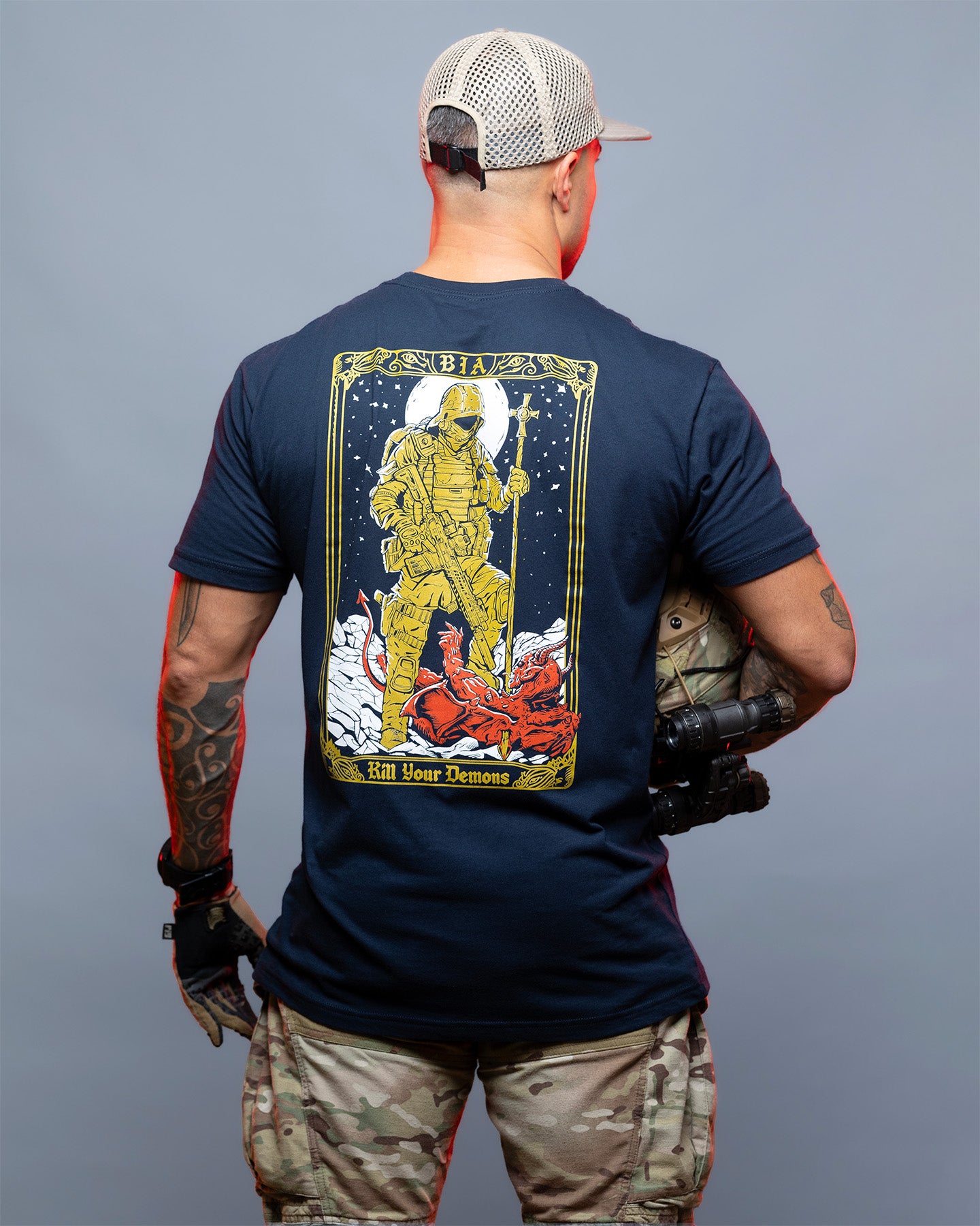 Person wearing a navy blue t-shirt with a graphic design on the back, standing against a gray background. #color_navy