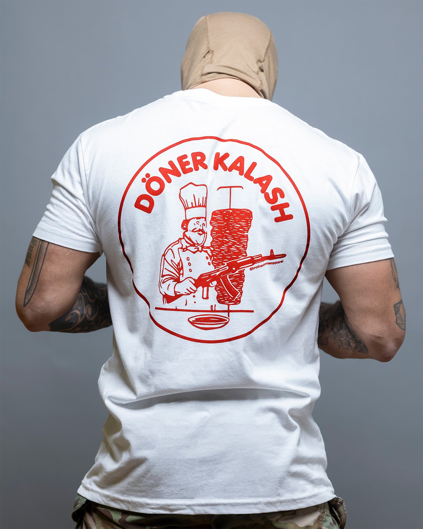 Person wearing a white t-shirt with a red graphic and text on the back, against a gray background. #color_white