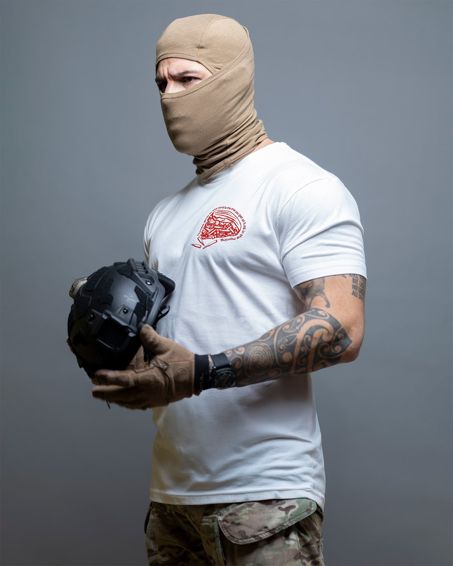 Person wearing a balaclava and holding a helmet against a gray background. #color_white