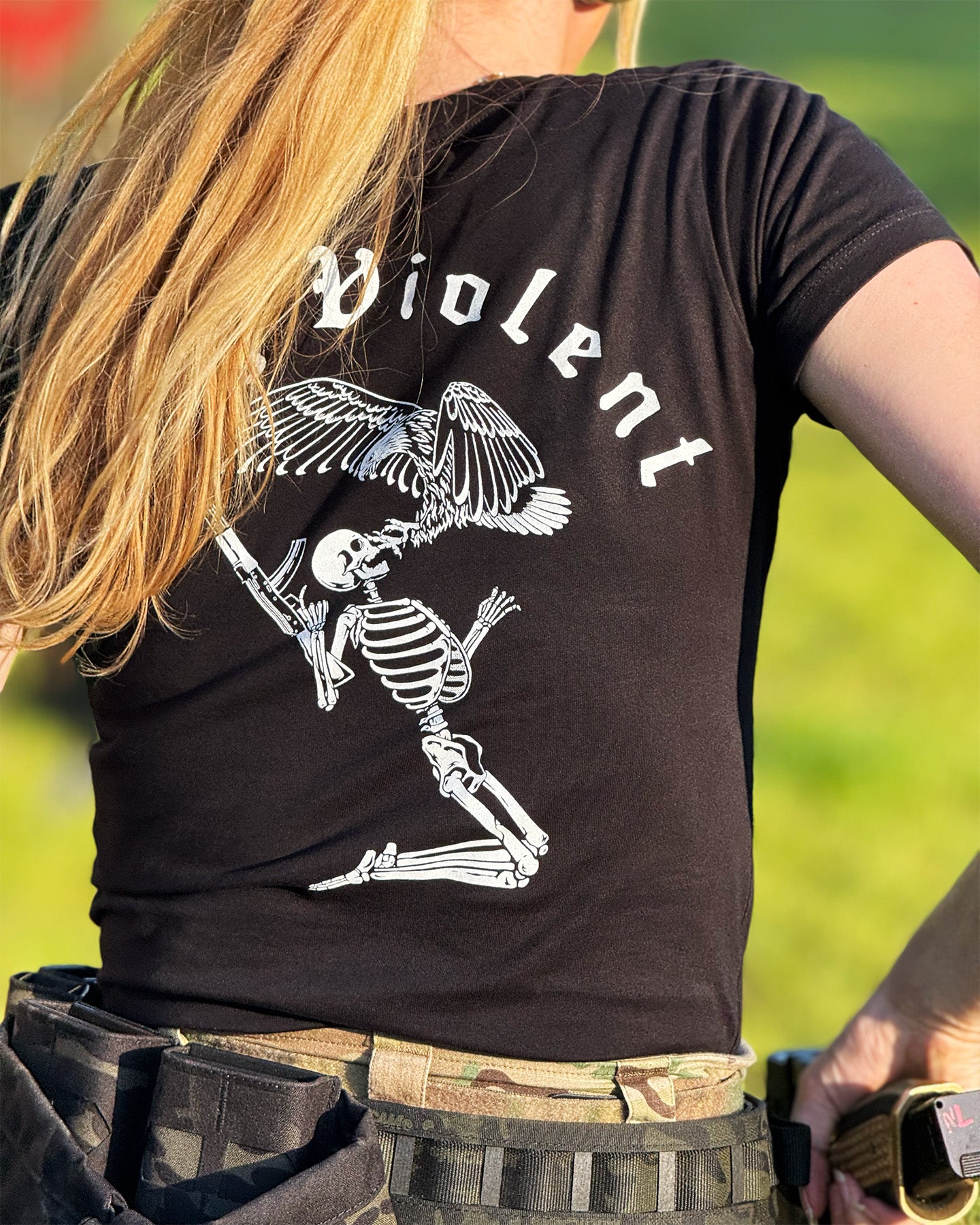 Person wearing a black t-shirt with a skeleton design and 'Stay Violent' text. #color_black #in_field