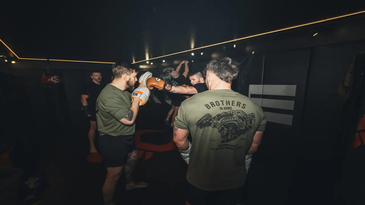 People in a gym are seen boxing. They are wearing Brothers in Arms Gear.