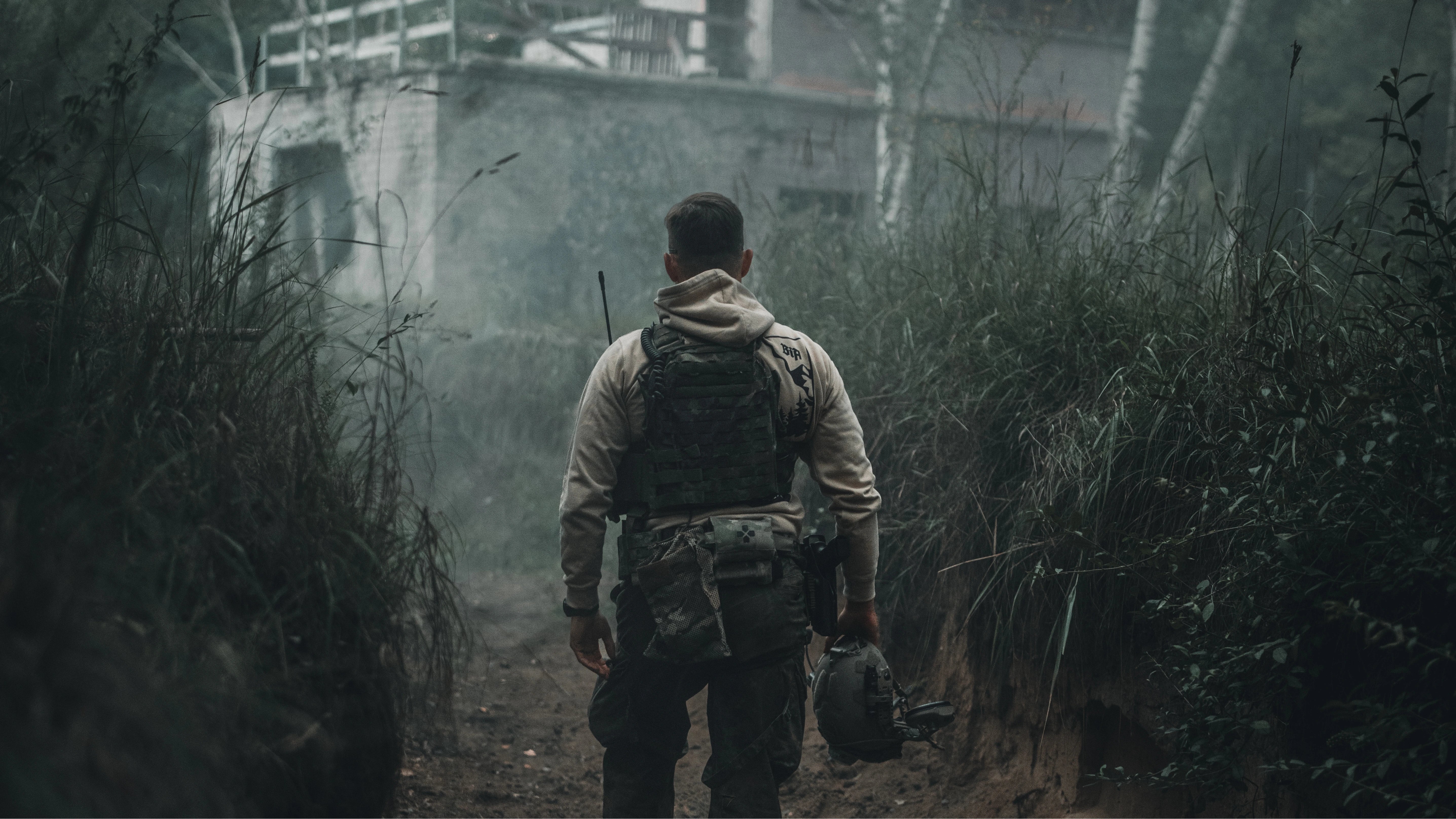 A man in military gear walking towards a building.
