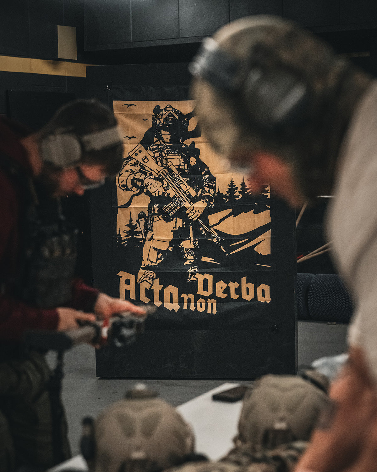 Acta Non Verba flag mounted above a table at a range day, shooters working in front of it