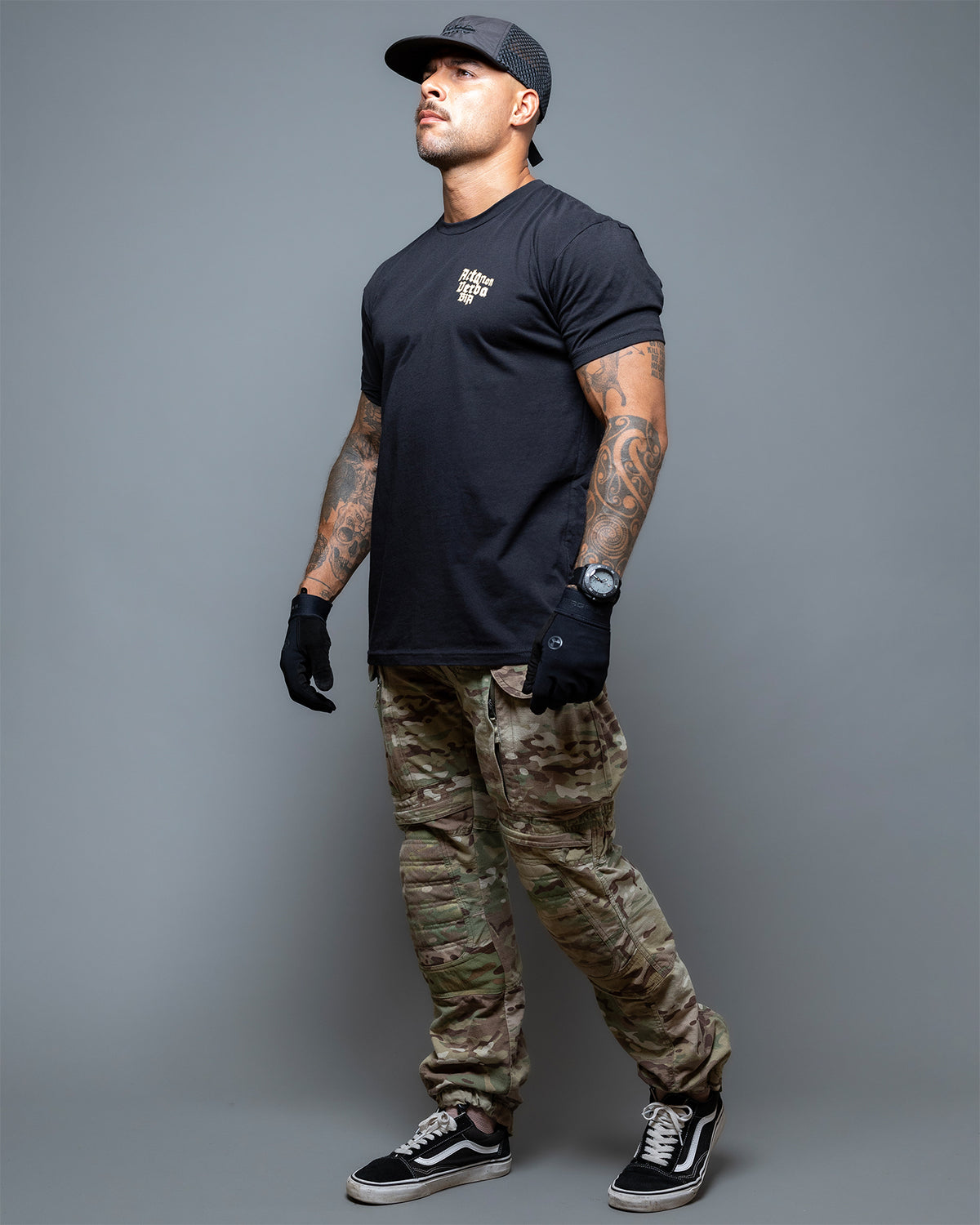 Full-length shot of the black Acta Non Verba T-Shirt worn with camo trousers