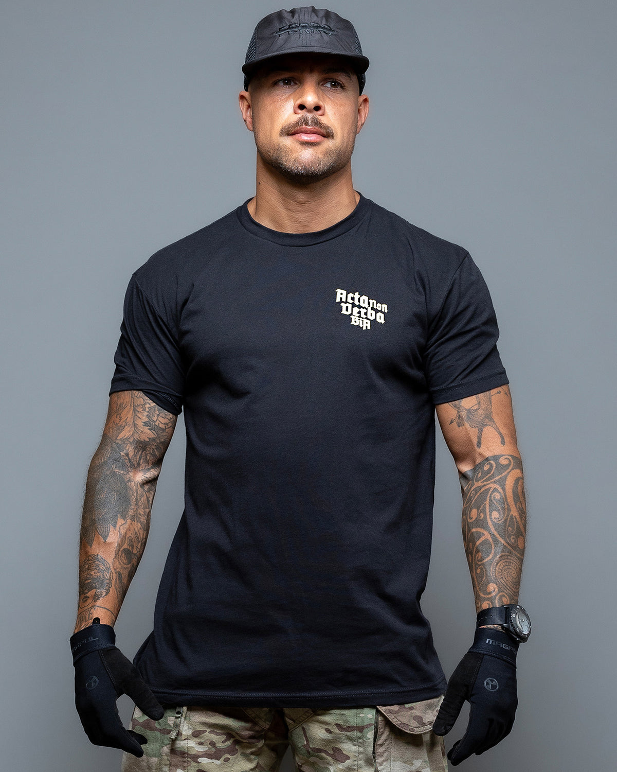 Man wearing the black Acta Non Verba T-Shirt, front view with the small chest print