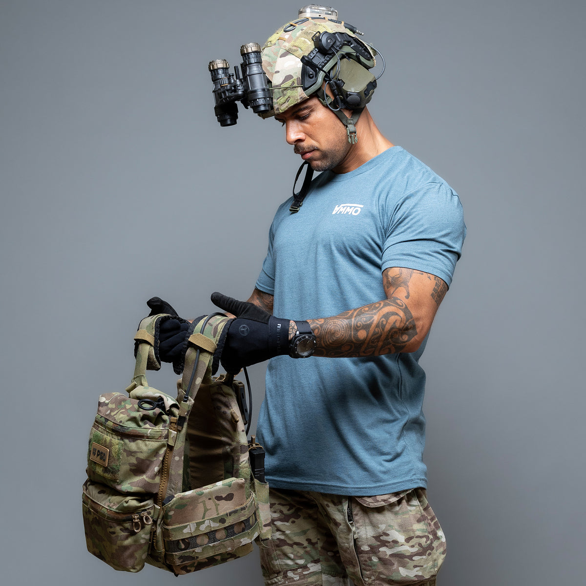 Man in a helmet with night vision wearing the indigo Ammo T-Shirt, holding a plate carrier