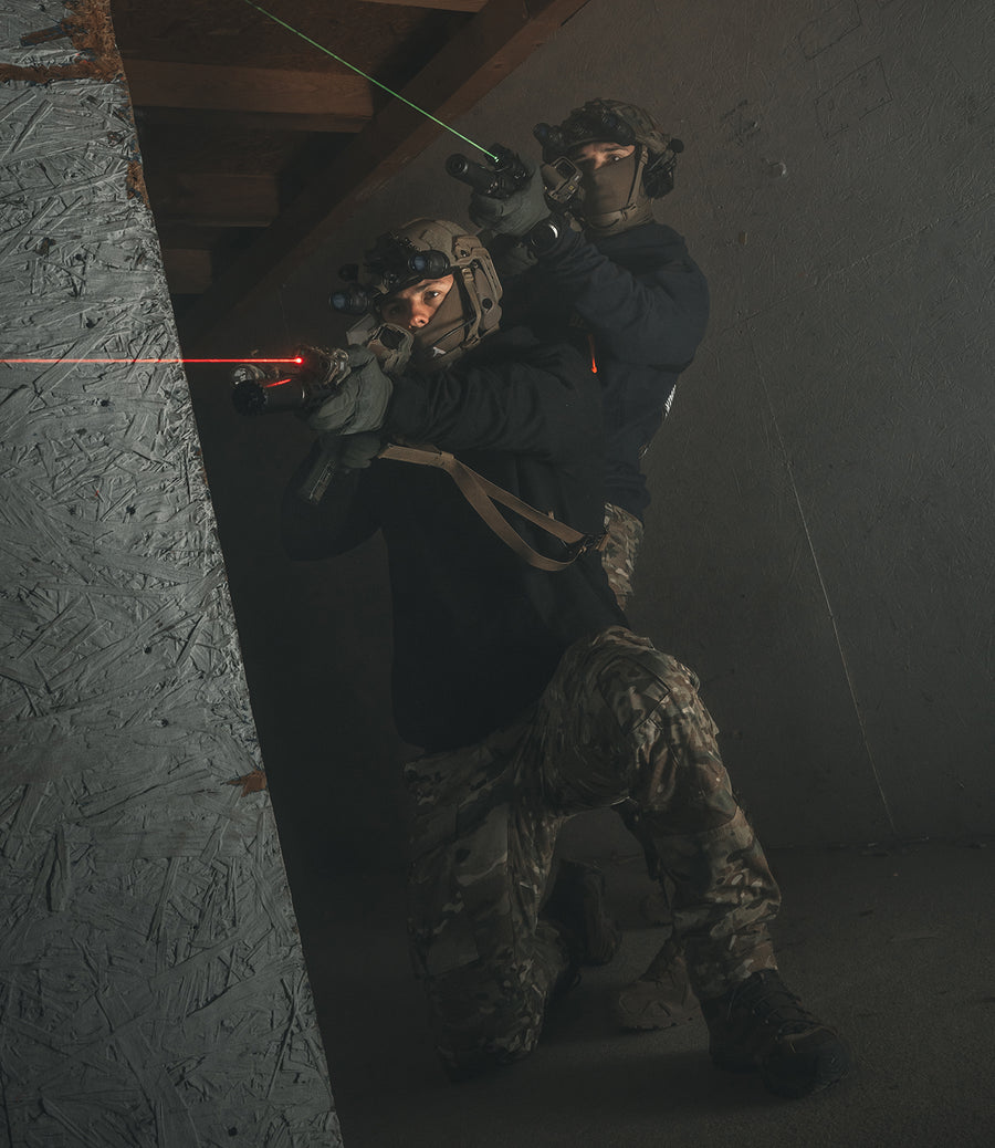 Two operators stacked at a wall during close quarters training, weapons up