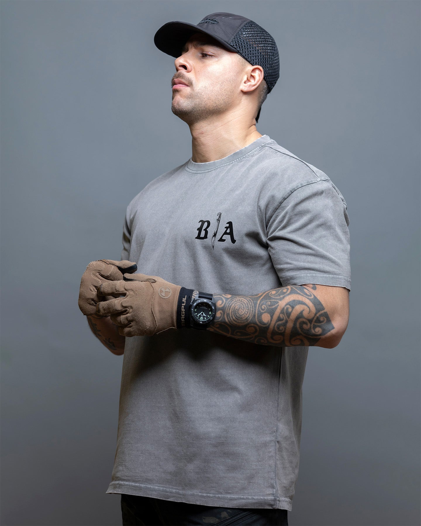 Man wearing a gray t-shirt with 'BIA' logo, gloves, and cap on a gray background. #color_gray