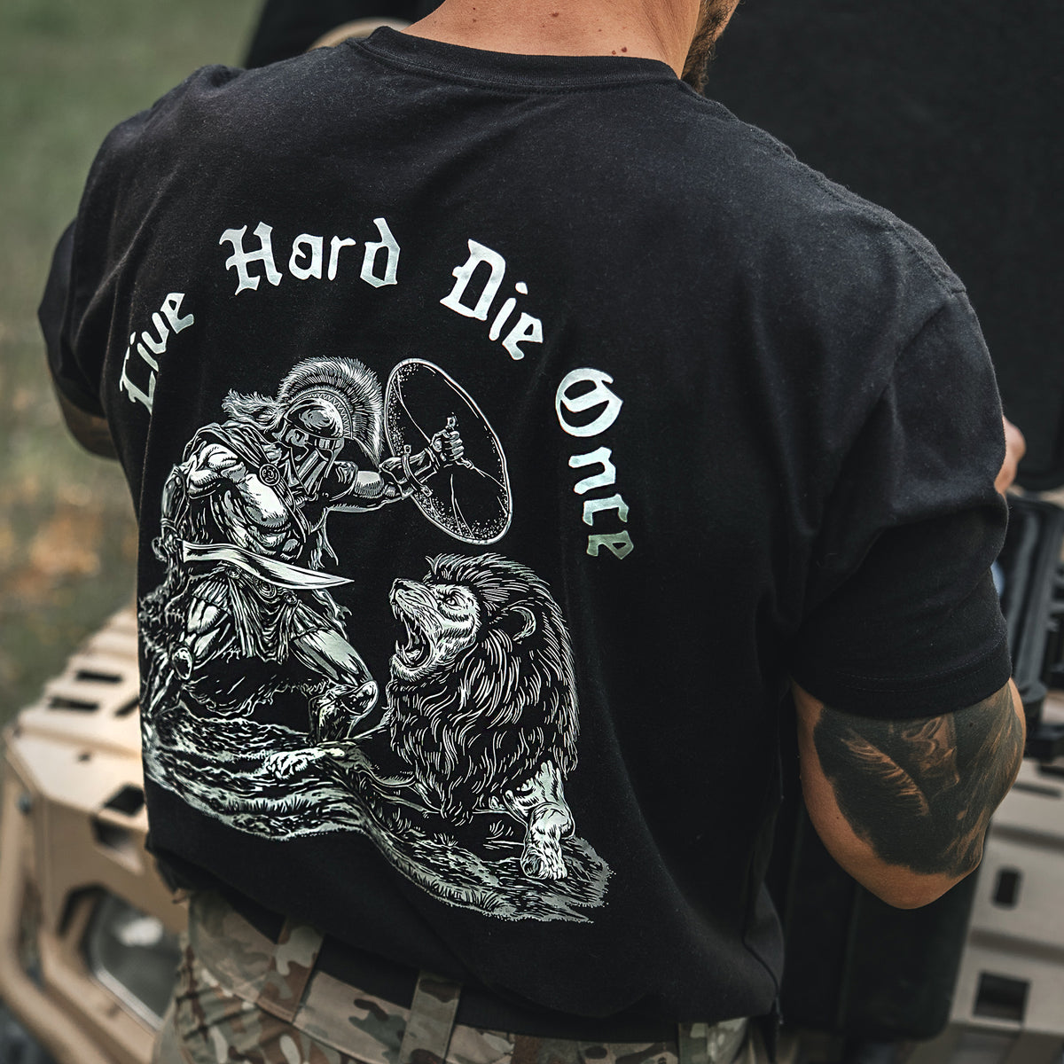 Man from behind in the black Live Hard Die Once T-Shirt with the reaper and lion back print