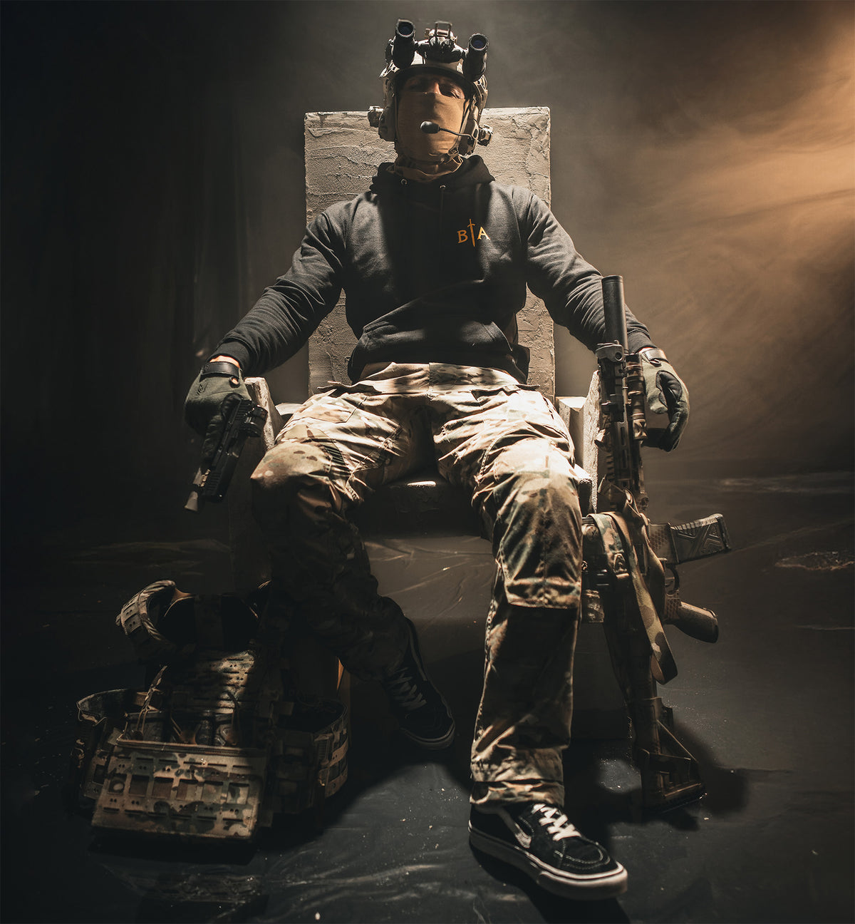 Person in tactical gear sitting on a stone throne with a rifle, wearing the I Shall Not Fear Hoodie