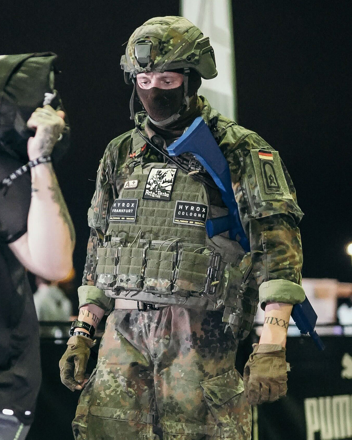 Soldier in full kit at an event with the Acta Non Verba patch on his plate carrier