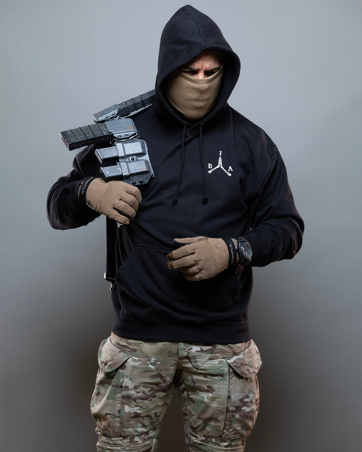 Man in the black Brothers in Arms Hoodie holding a rifle, worn with camo trousers