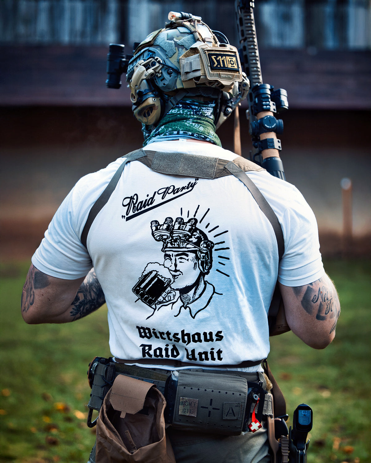 Man from behind in the white Raid Party T-Shirt with a plate carrier on a training ground