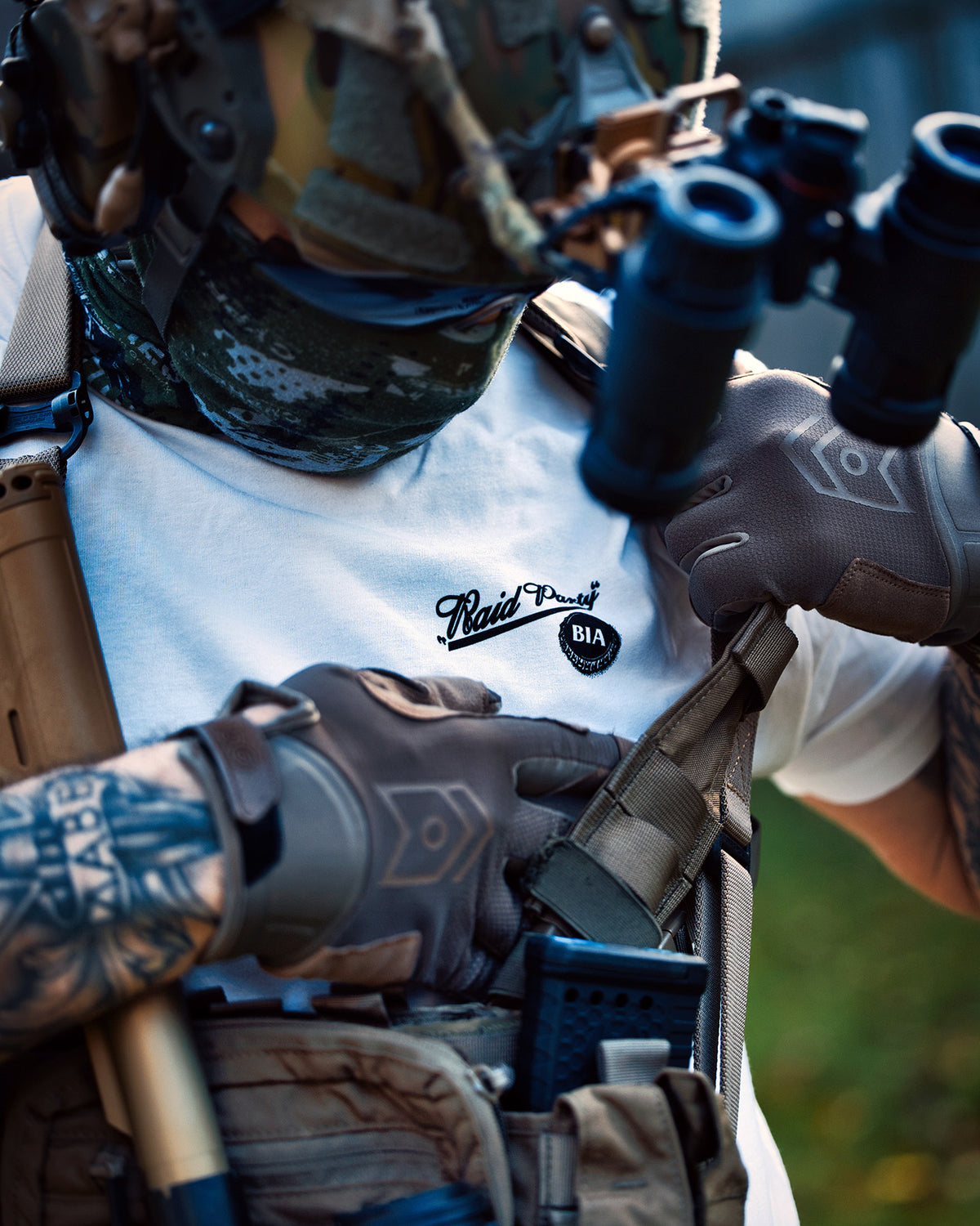 Close-up of a shooter behind a rifle, wearing the white Raid Party T-Shirt