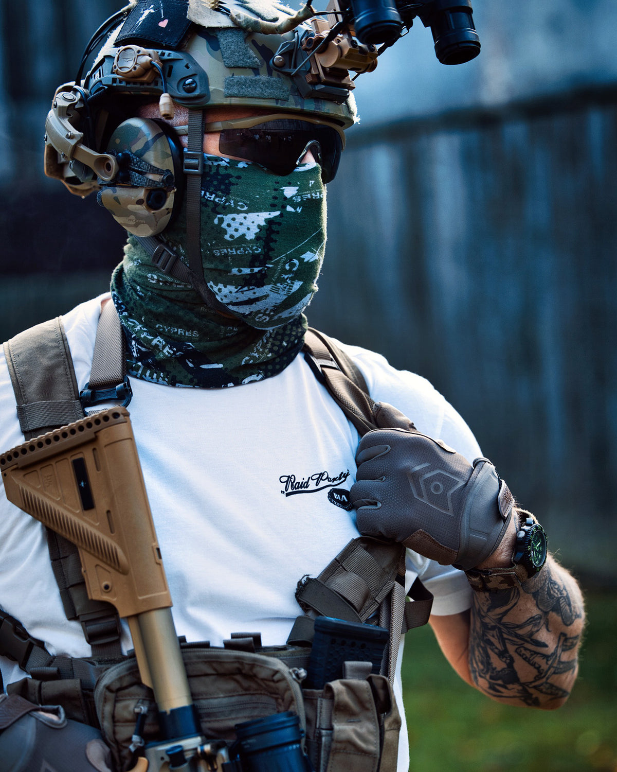 Man with helmet, face mask and rifle wearing the white Raid Party T-Shirt outdoors