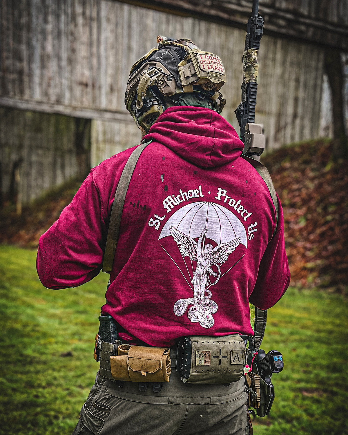 Man from behind in the bordeaux St. Michael Hoodie with helmet and rifle outdoors