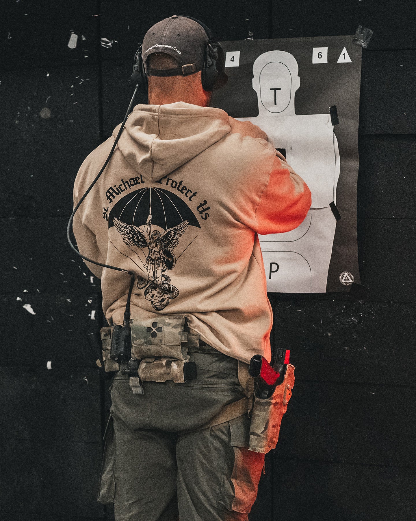 Man from behind in the sand St. Michael Hoodie at an indoor range in front of a target #color_sand #in_field