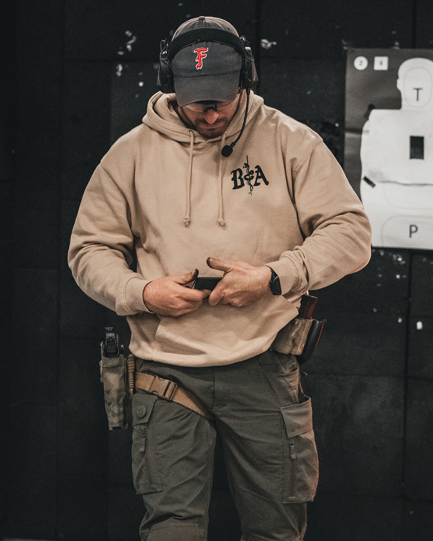Man in a cap and ear protection wearing the sand St. Michael Hoodie at the range #color_sand #in_field