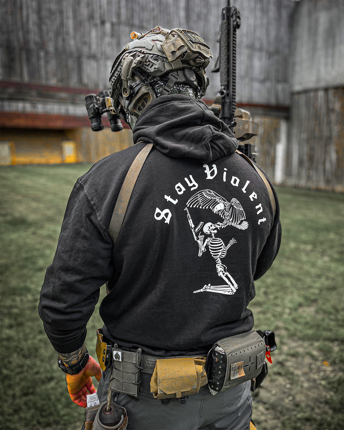 Man from behind in the black Stay Violent Hoodie with a rifle on a training ground