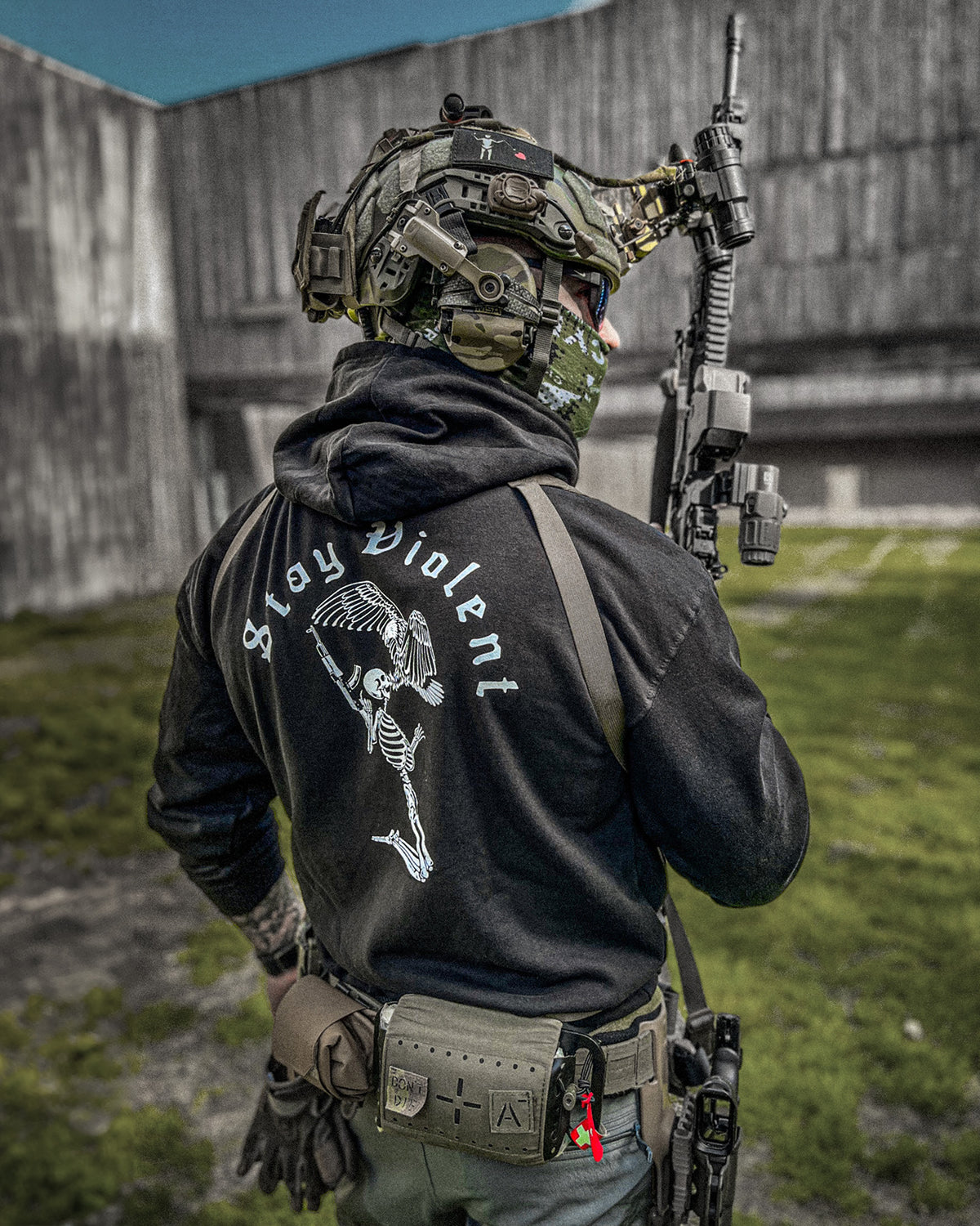 Man from behind in the black Stay Violent Hoodie with helmet and rifle outdoors