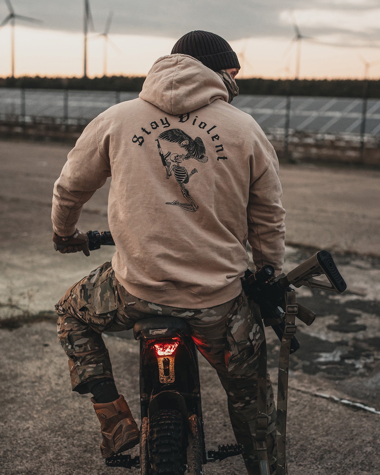 Man from behind on a motorcycle in the sand Stay Violent Hoodie, skeleton back print #color_sand #in_field