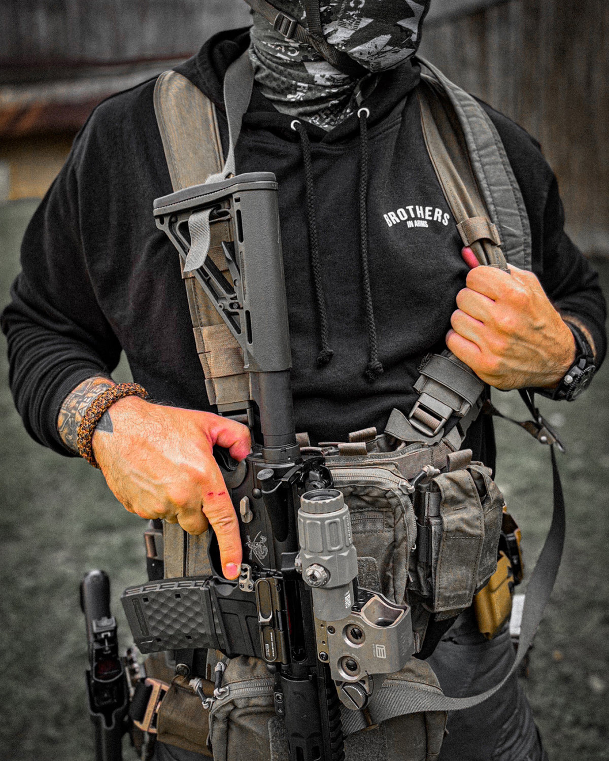 Man with a chest rig and rifle wearing the black Team Hoodie, close-up