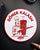 Circular Coin with a Döner Kebab chef and rifle on a dark surface, with the text "Döner Kalash"