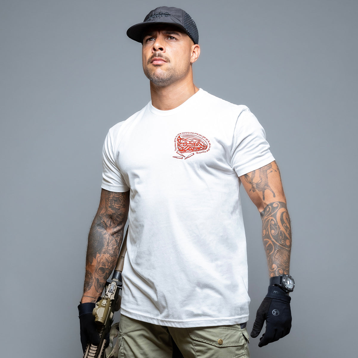 Man in a cap holding a rifle, wearing the white Döner Kalash T-Shirt with the red chest print