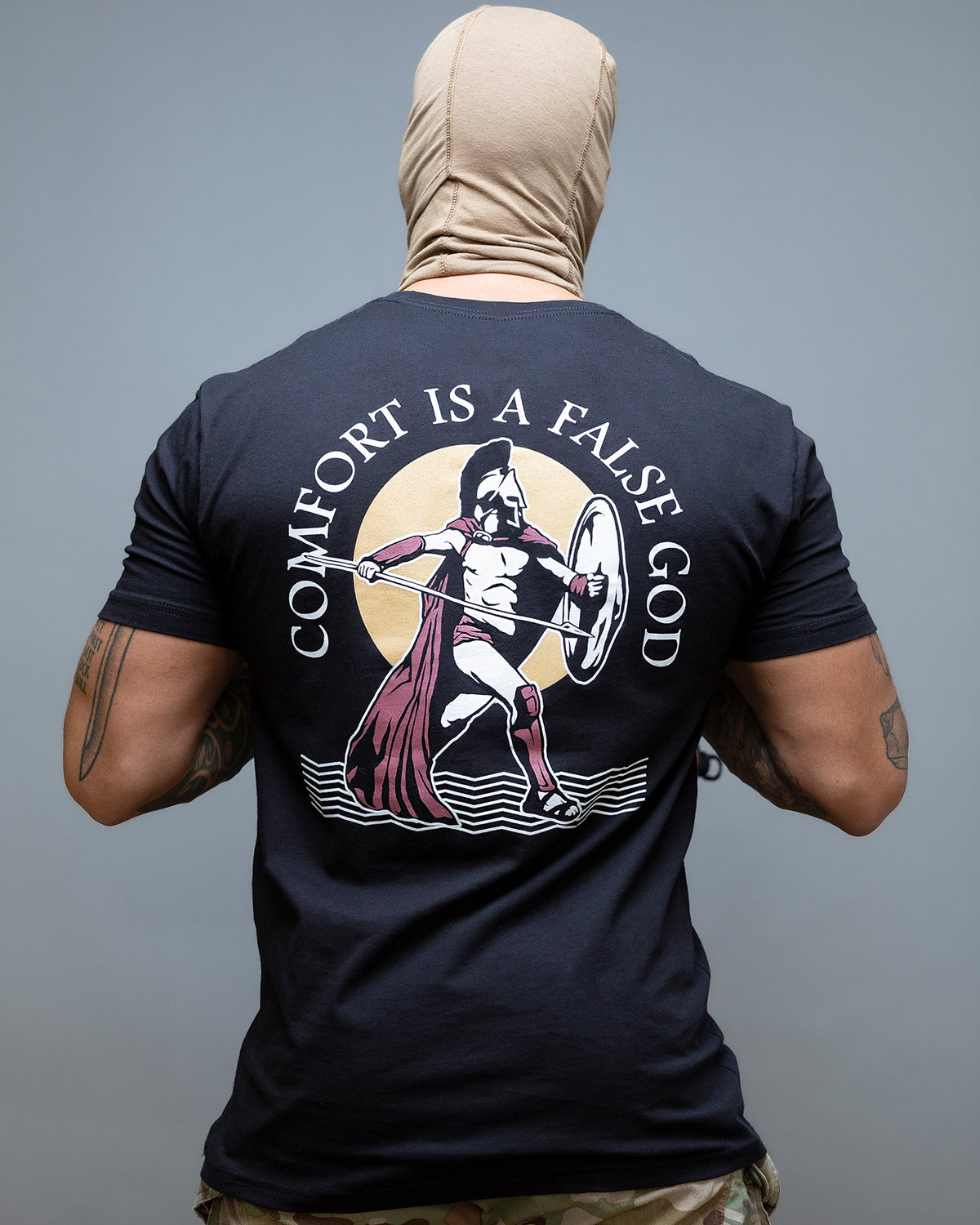 Rear view of the black Comfort Is A False God T-Shirt with the Spartan back print