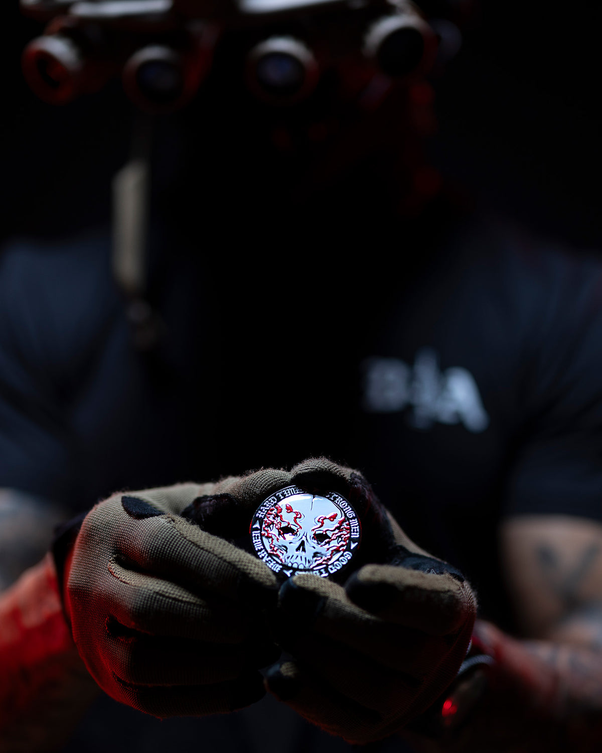 Hard Times coin held up in a gloved hand, lit red in the dark