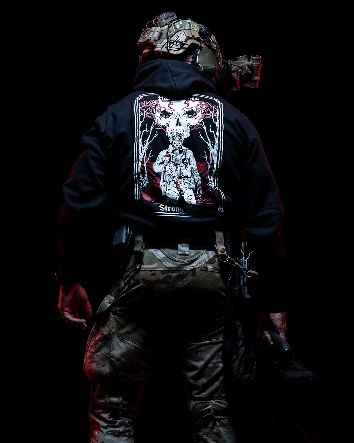 Man from behind in the black Hard Times Hoodie lit red against a dark background #color_black #in_field