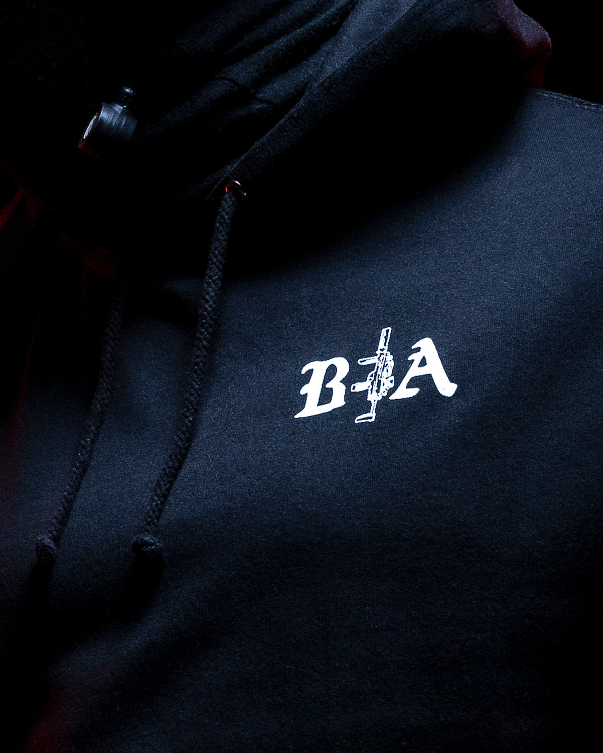 Close-up of the B|A chest logo on the black Hard Times Hoodie #color_black #in_field