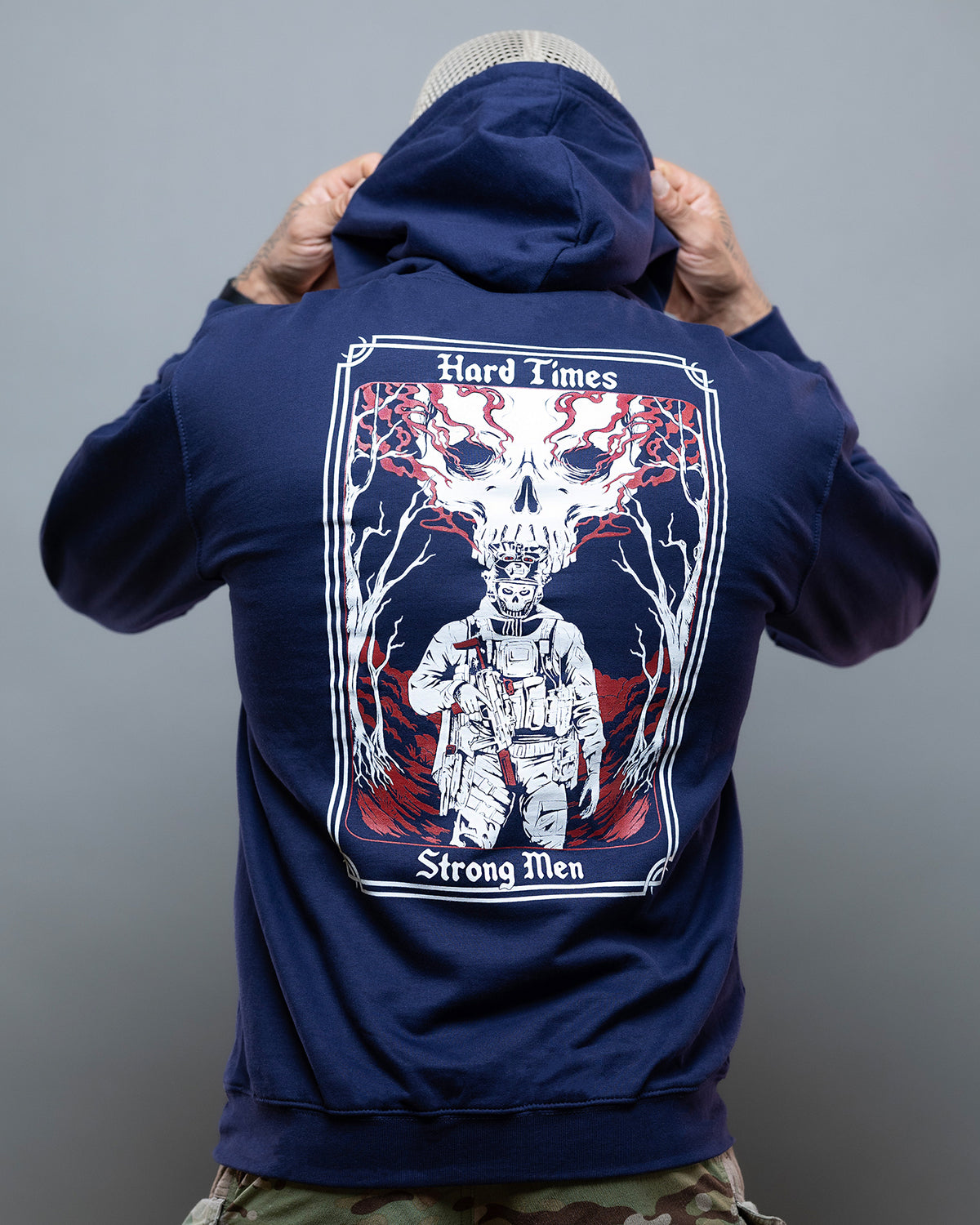 Man from behind pulling up the hood of the navy Hard Times Hoodie, tarot card back print