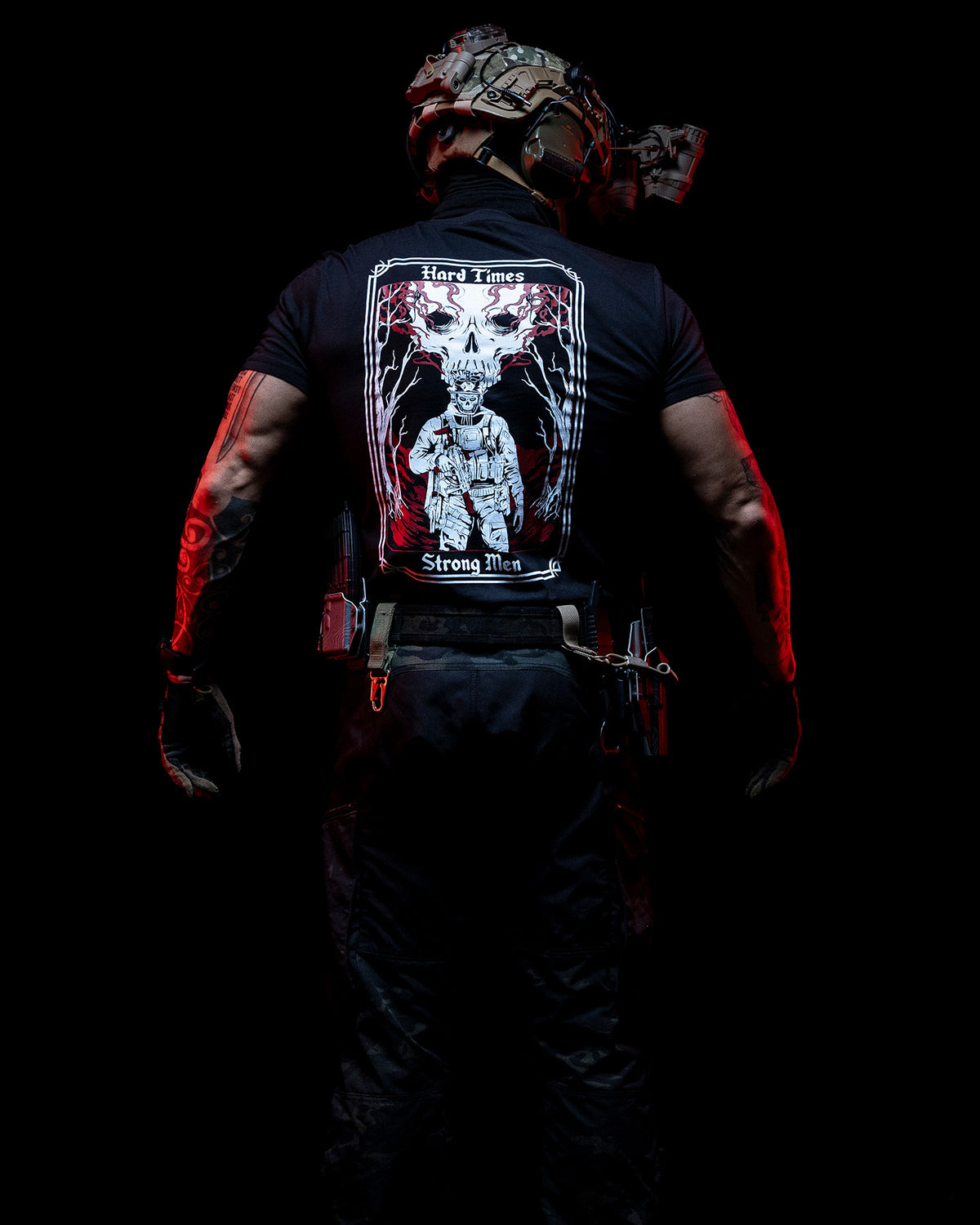 Man from behind in the black Hard Times T-Shirt against a dark background