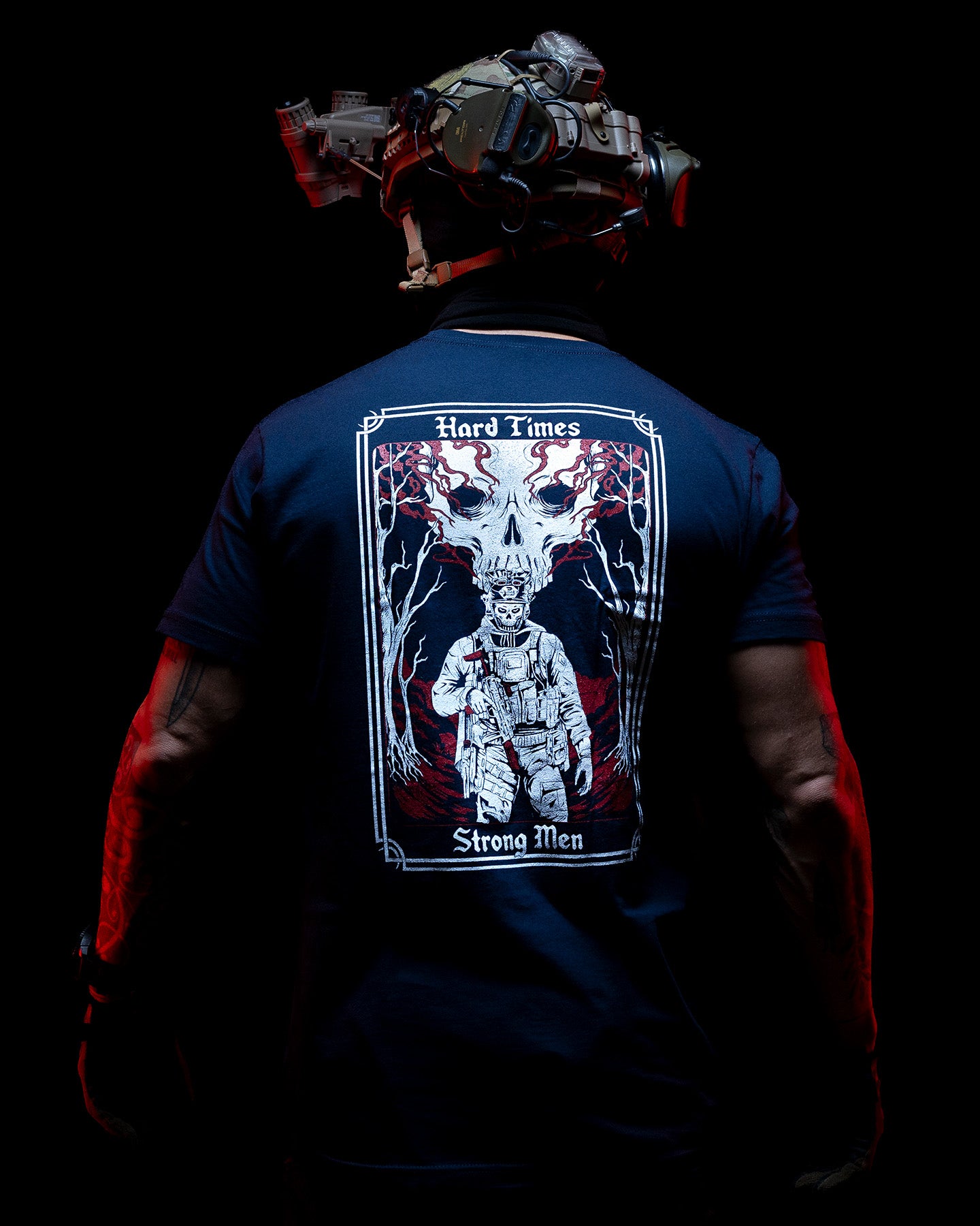 Man from behind in the navy Hard Times T-Shirt with a helmet, lit red in the dark #color_navy #in_field