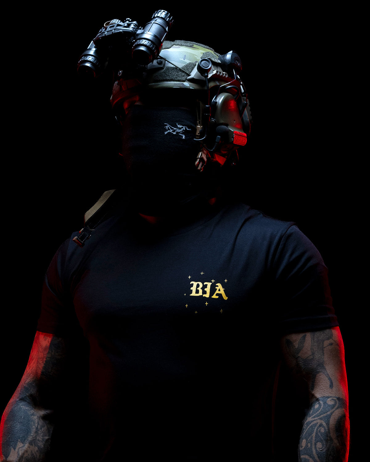 Close-up of the gold chest print on the black Eyes On The Horizon T-Shirt in red light