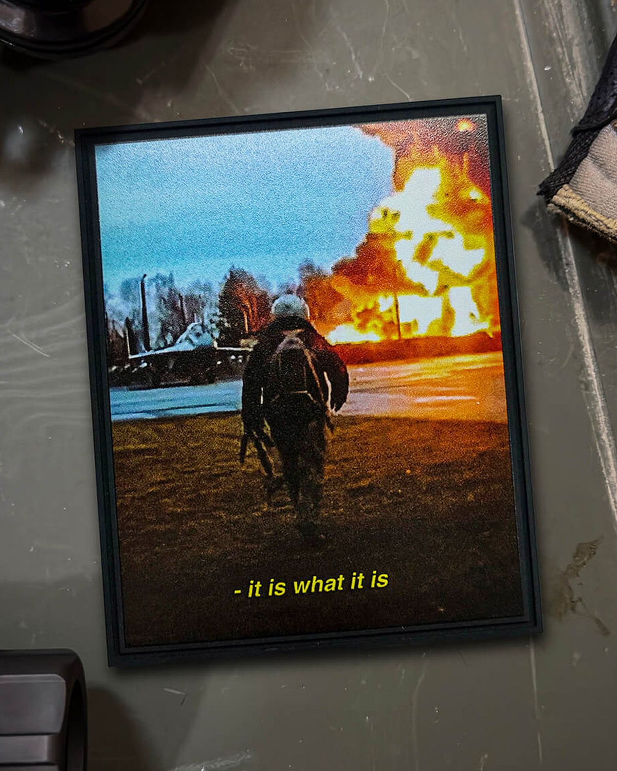 Framed It Is What It Is print showing a soldier walking away from an explosion