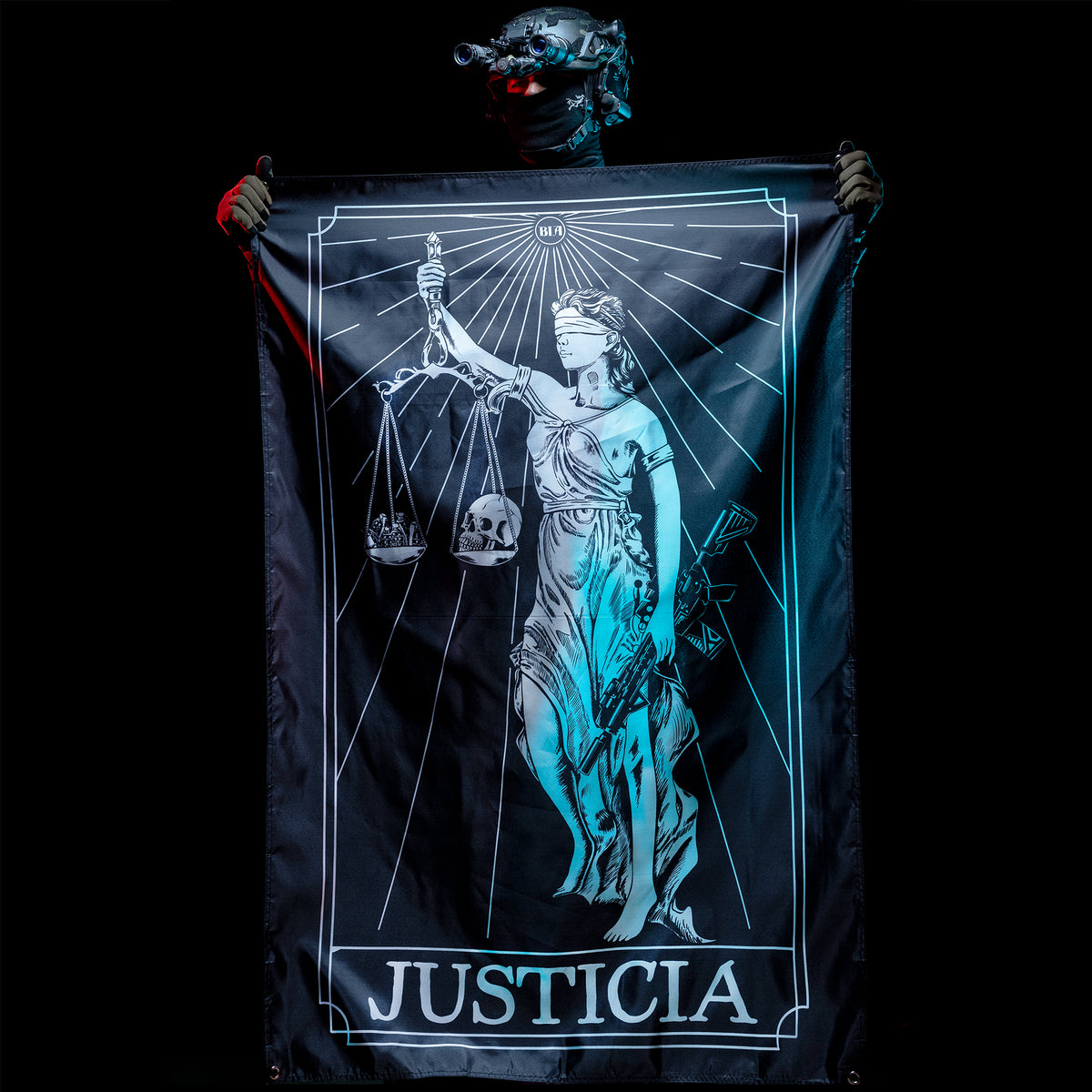 Person in a helmet holding up the Justicia flag, lit teal against a black background