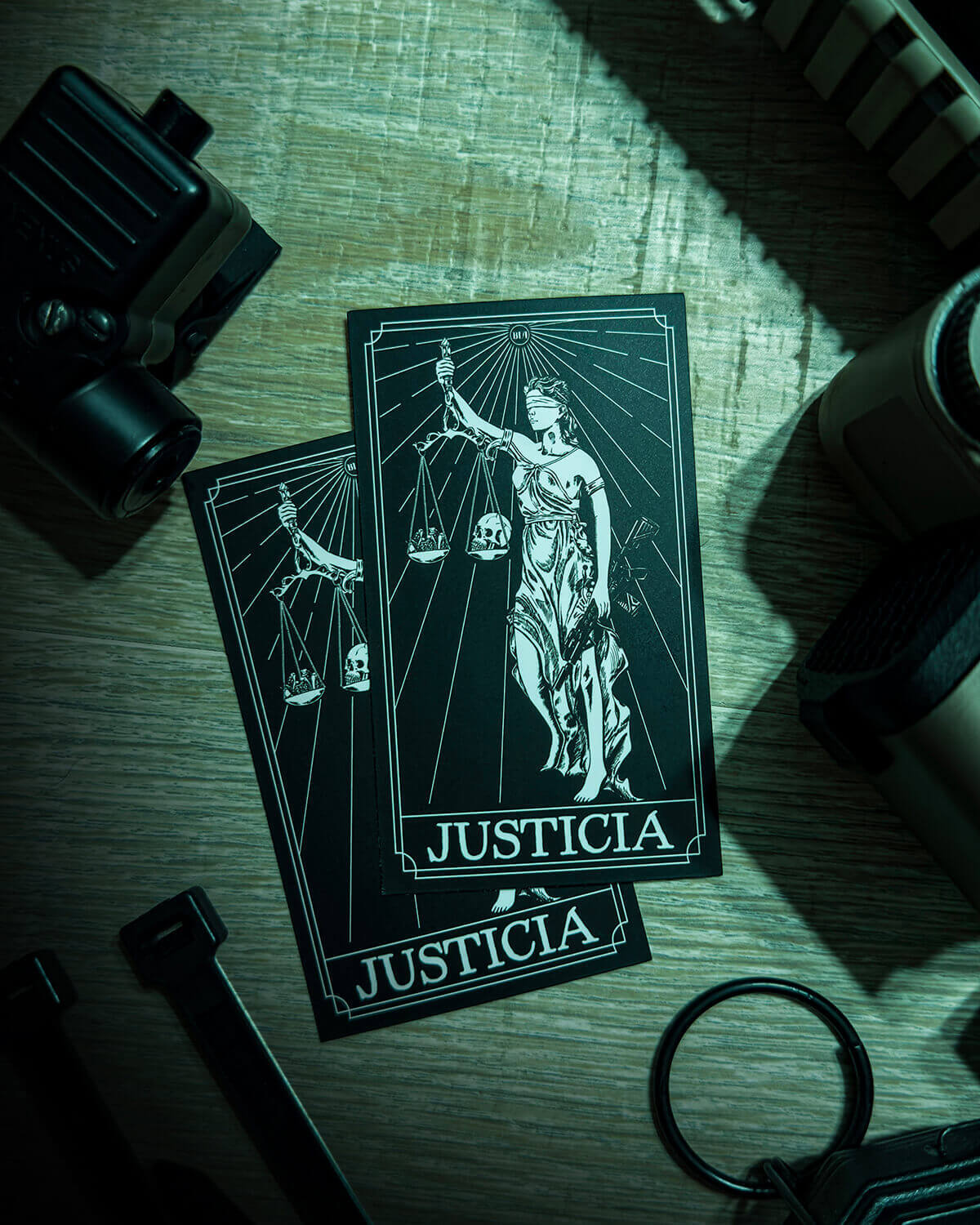 Two Justicia stickers on a green surface next to tactical gear