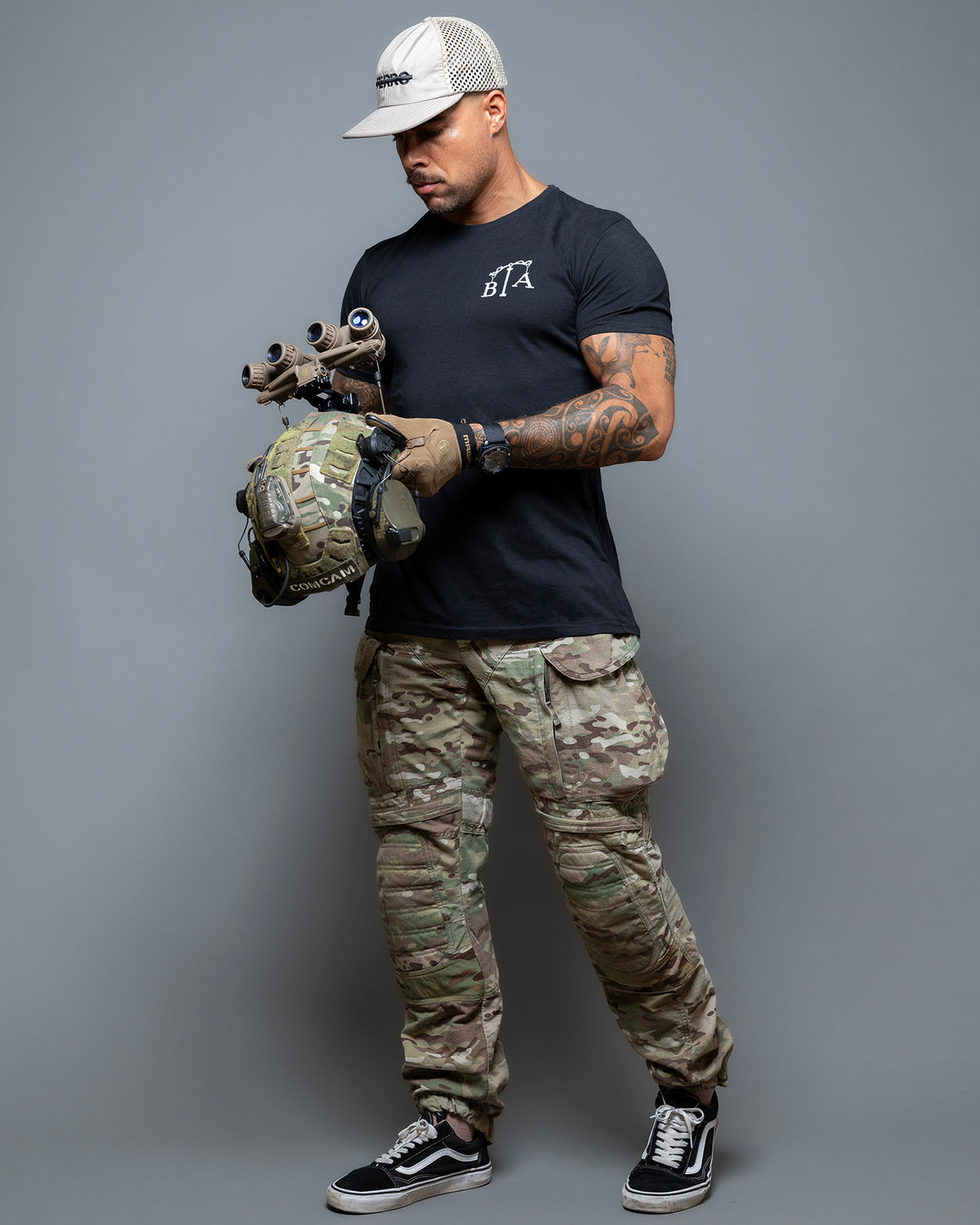 Full-length shot of the black Justicia T-Shirt worn with camo trousers and a cap