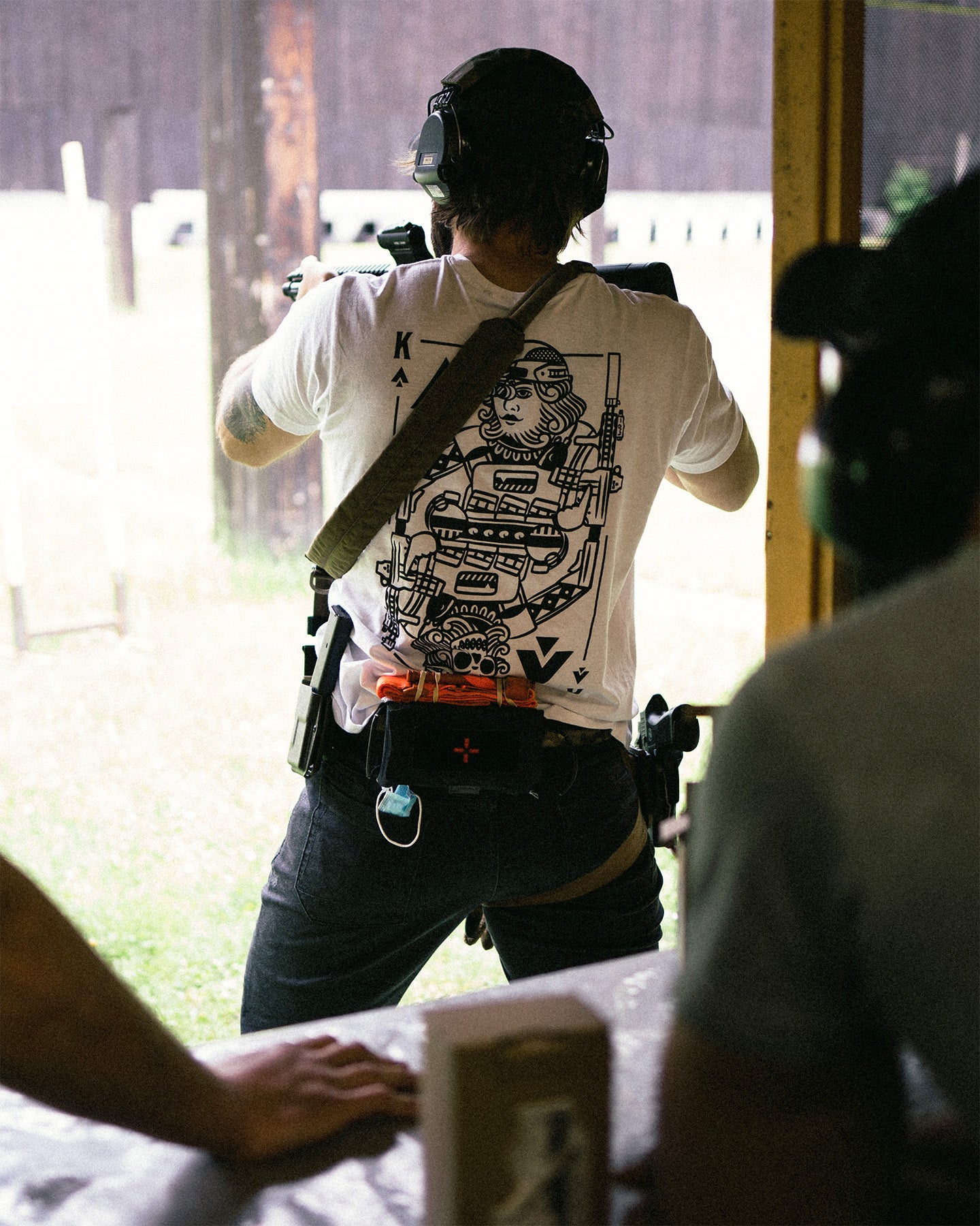 Person at a shooting range from behind, playing card back print on the white King of Spades T-Shirt #color_white #in_field