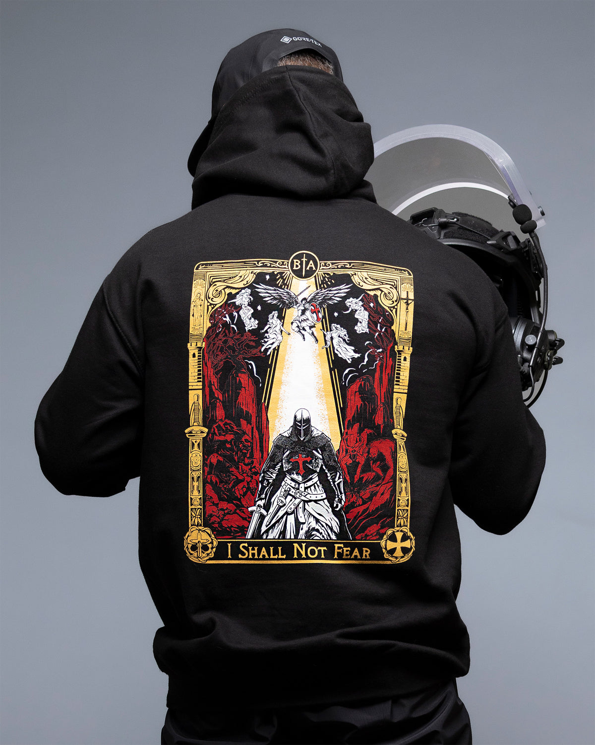 Man from behind with the hood up and a helmet, wearing the black No Fear Hoodie with the back print