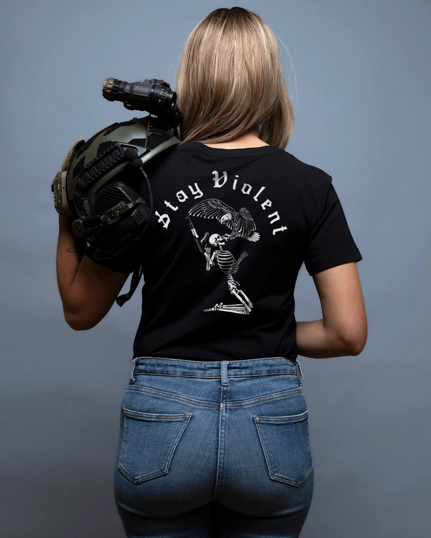 Person wearing a black t-shirt with 'Stay Violent' text and a skull design, holding a helmet. #color_black