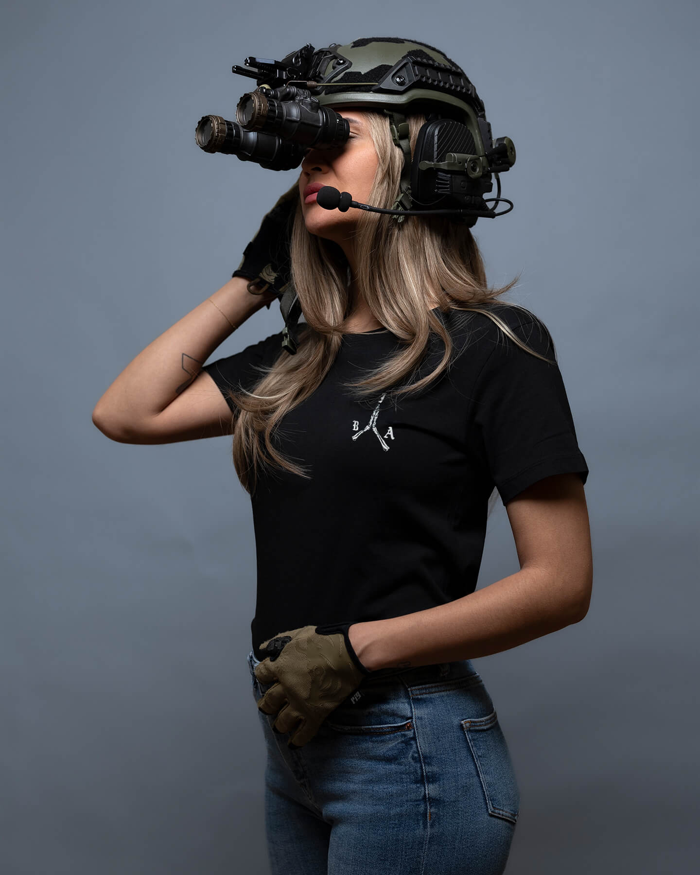Person wearing a tactical helmet with a camera attachment on a gray background. #color_black