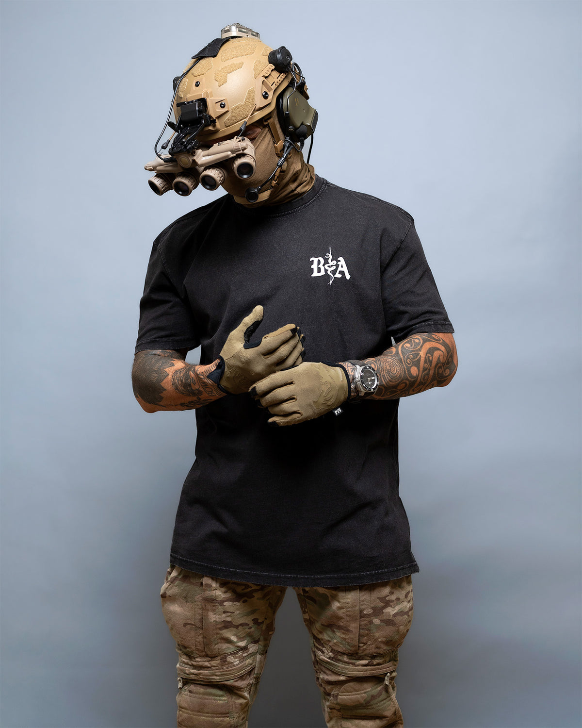 Man with a helmet wearing the black St. Michael Oversized Shirt with camo trousers